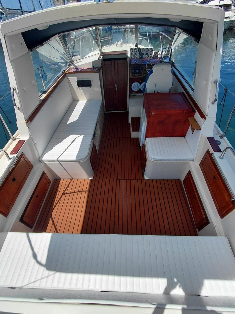 Il pozzetto della barca con pavimento in teak e sedute bianche
