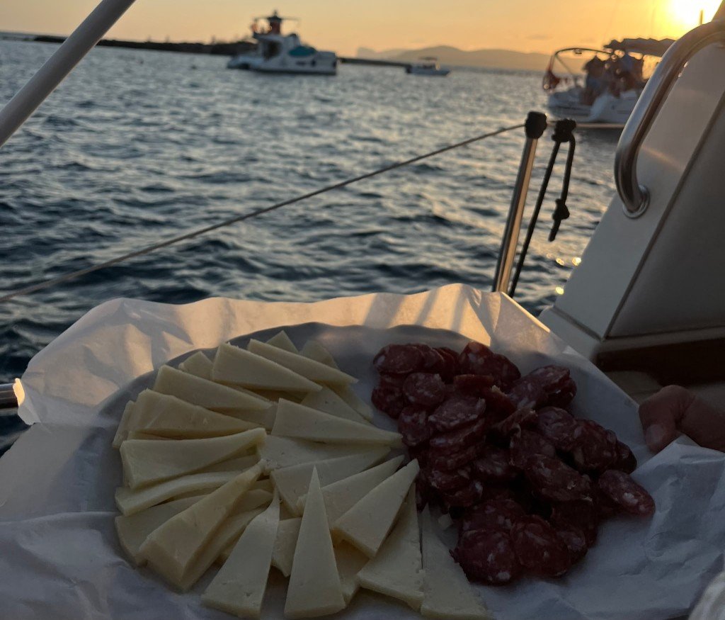 Aperitivo con formaggi e salumi a bordo al tramonto