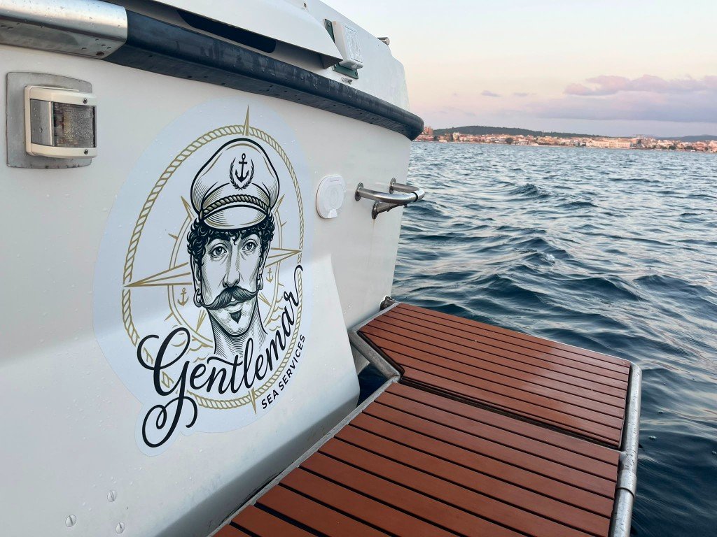 Logo GentleMar Sea Services sullo specchio di poppa al tramonto ad Alghero